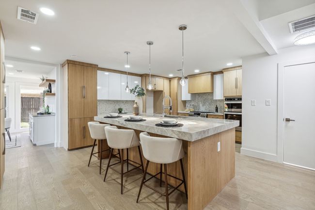 Kitchen with a spacious island, light wood-style floors, visible vents, and a sink | Image 16