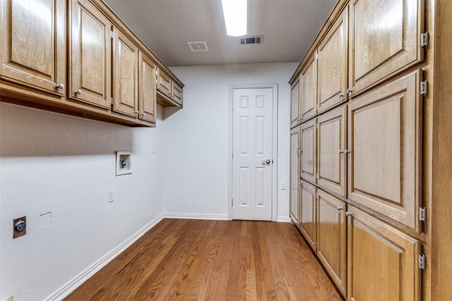 Laundry area with cabinet space, wood finished floors, baseboards, hookup for a washing machine, and electric dryer hookup | Image 23