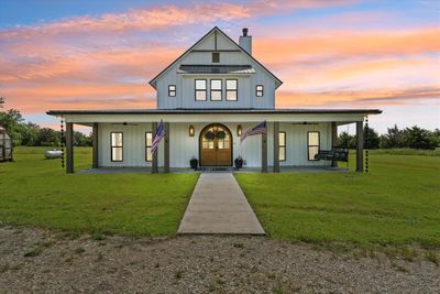 Modern farmhouse featuring covered porch, a lawn, and ceiling fan | Image 1