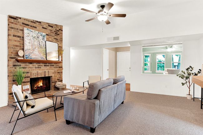 Living area with a ceiling fan, carpet, and a brick fireplace | Image 4