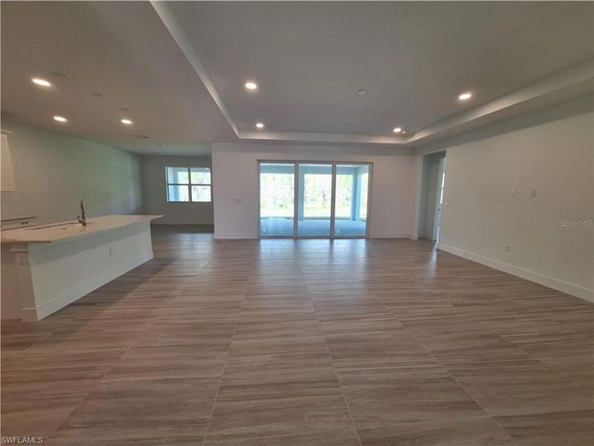 Great room with tray ceiling and 12' hurricane resistant sliding glass doors | Image 6