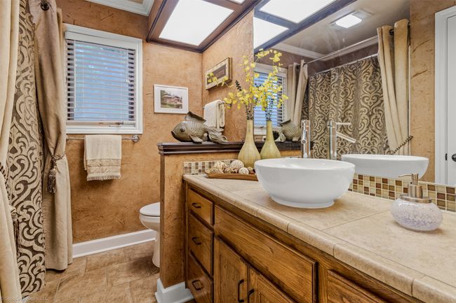 Elegant guest bathroom with tile flooring, tub/shower combo and decorative lighting | Image 21
