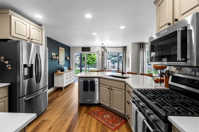 Kitchen featuring appliances with stainless steel finishes, a chandelier, recessed lighting, light wood-style flooring, and a peninsula | Image 4