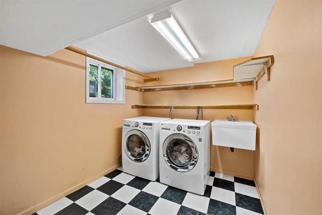 Basement Laundry room featuring sink, dark tile flooring, and washer and clothes dryer | Image 25
