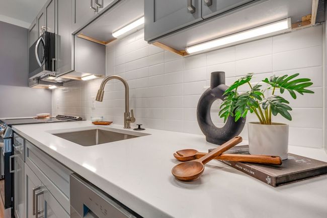 Kitchen with gray cabinetry, a sink, stainless steel microwave, and backsplash | Image 9