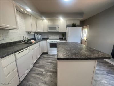 Kitchen with backsplash, sink, white appliances, and white cabinets | Image 3