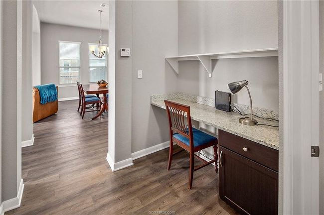 Office area with dark hardwood / wood-style flooring and a notable chandelier | Image 17