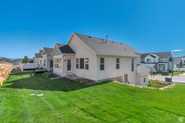 Rear view of house featuring stucco siding, a lawn, entry steps, a residential view, and a shingled roof | Image 5