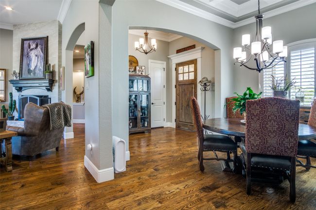 Dining space with wood finished floors, ornamental molding, and a chandelier | Image 4