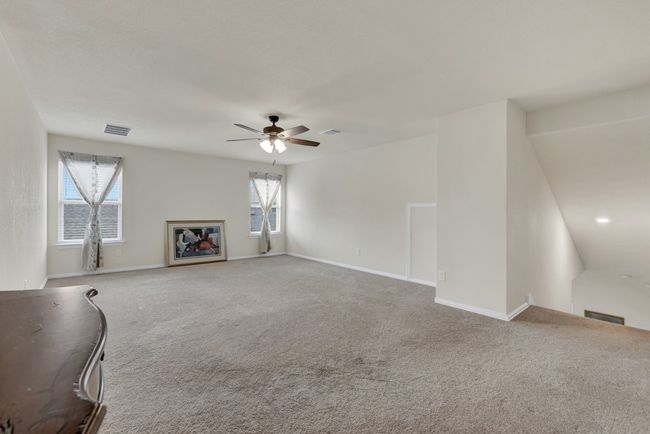 Unfurnished living room featuring carpet flooring, baseboards, a ceiling fan, and visible vents | Image 25