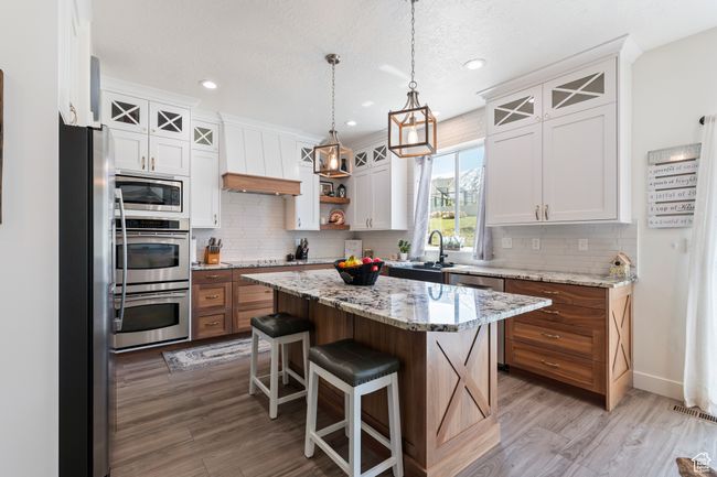 Kitchen with premium range hood, backsplash, stainless steel appliances, and light wood-style floors | Image 16
