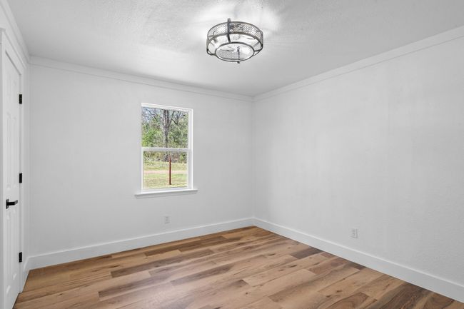 Empty room with light wood-type flooring, an inviting chandelier, baseboards, and a textured ceiling | Image 31