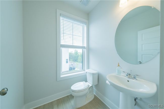 Bathroom featuring baseboards, toilet, wood finished floors, and a sink | Image 19