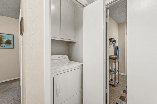 Laundry area featuring washer / clothes dryer, baseboards, a textured ceiling, and cabinet space | Image 16