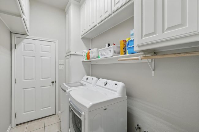 Laundry room featuring cabinet space, separate washer and dryer, and light tile patterned flooring | Image 34