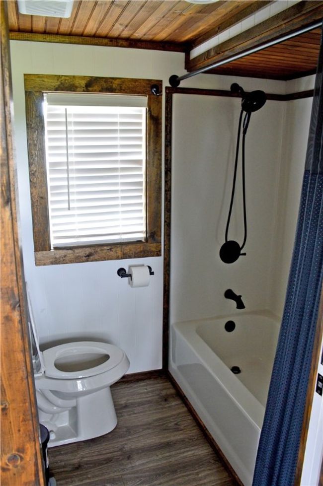 Bathroom featuring toilet, wood finished floors, shower / tub combo with curtain, and wooden ceiling | Image 18