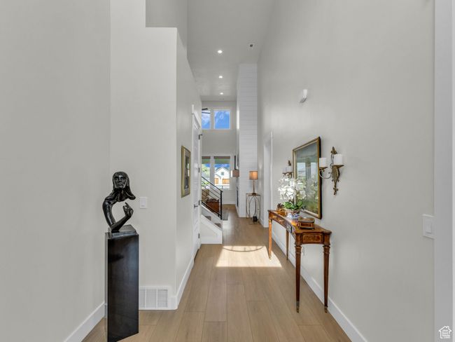 Corridor featuring light wood-style floors, recessed lighting, baseboards, and a high ceiling | Image 5