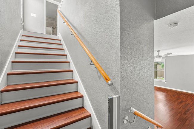 Stairs with a textured wall, wood finished floors, and a ceiling fan | Image 15