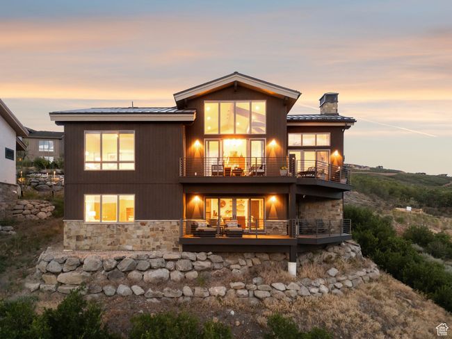 Back of property featuring a balcony, stone siding, a chimney, and a metal roof | Image 65