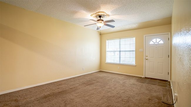 Carpeted entrance foyer with ceiling fan, a textured ceiling, and baseboards | Image 6