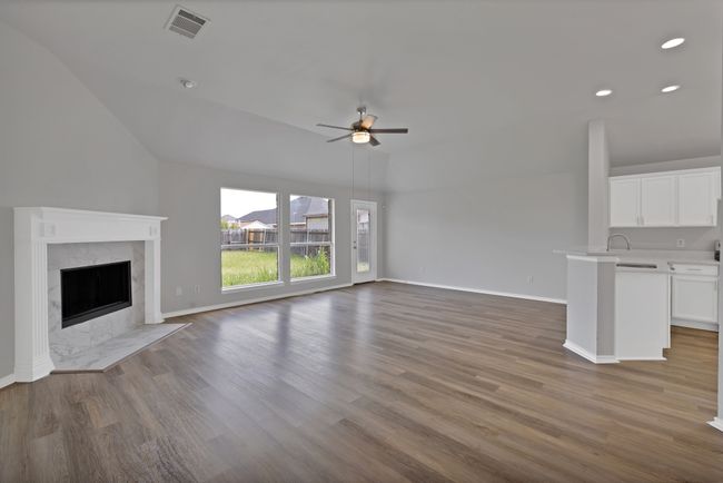 Unfurnished living room with a ceiling fan, lofted ceiling, wood finished floors, a high end fireplace, and recessed lighting | Image 8