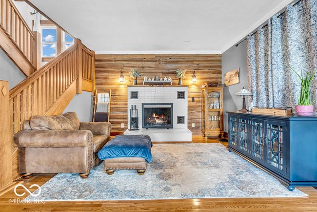 living area with log walls, stairway, wood finished floors, and a warm lit fireplace | Image 20