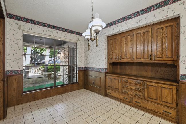 Unfurnished dining area with wainscoting, wallpapered walls, a chandelier, and light tile patterned floors | Image 16