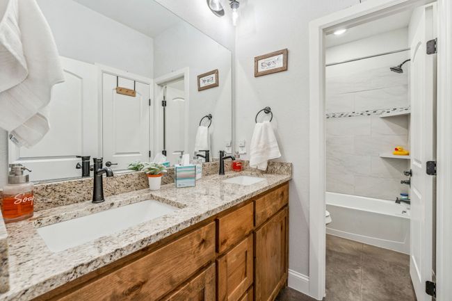Bathroom featuring double vanity, toilet, and tub / shower combination | Image 19