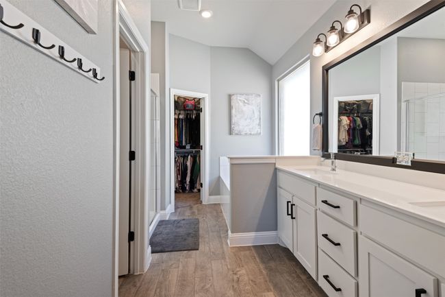 Full bathroom with wood finished floors, a sink, vaulted ceiling, a shower stall, and a walk in closet | Image 24