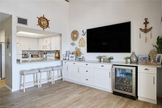 Kitchen featuring white appliances, beverage cooler, light hardwood / wood-style flooring, and white cabinets | Image 8