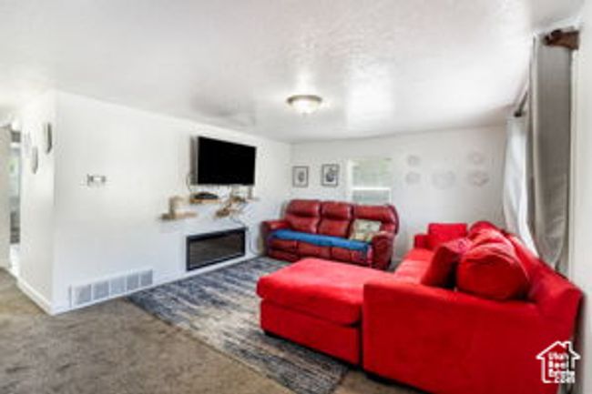 Carpeted living room featuring visible vents and a fireplace | Image 8