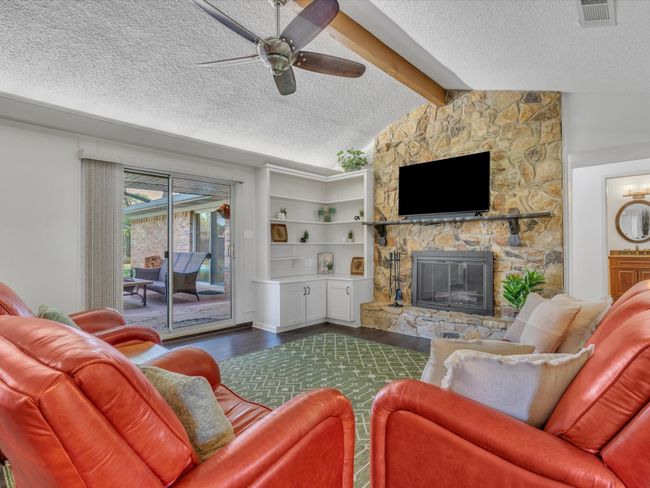 Living area featuring a textured ceiling, dark wood-style flooring, ceiling fan, and a fireplace | Image 9