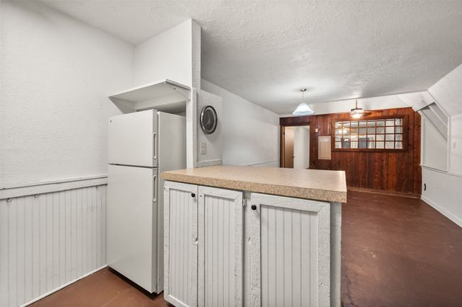 Kitchen featuring a peninsula, light countertops, freestanding refrigerator, and finished concrete floors | Image 10
