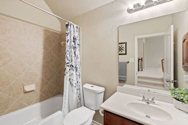 Full bath featuring vanity, a textured wall, and shower / bath combo with shower curtain | Image 23