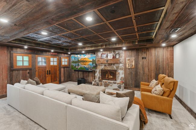 Carpeted living area with wooden walls, french doors, and a stone fireplace | Image 38