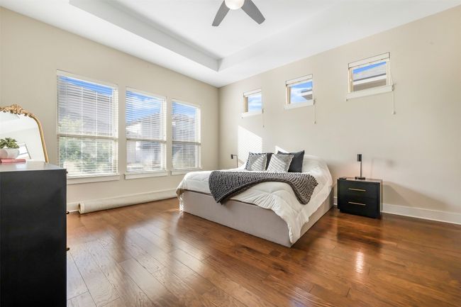 Bedroom featuring hardwood / wood-style flooring, a raised ceiling, and ceiling fan | Image 17