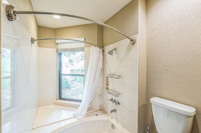 Full bath featuring toilet, a textured wall, and shower / tub combo with curtain | Image 23