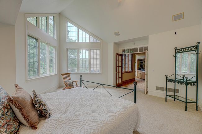 The main level primary suite offers a sanctuary of its own featuring brand new carpet, a private bath, a spacious walk-in closet complete with a built-in organization system, and serene nature views | Image 18