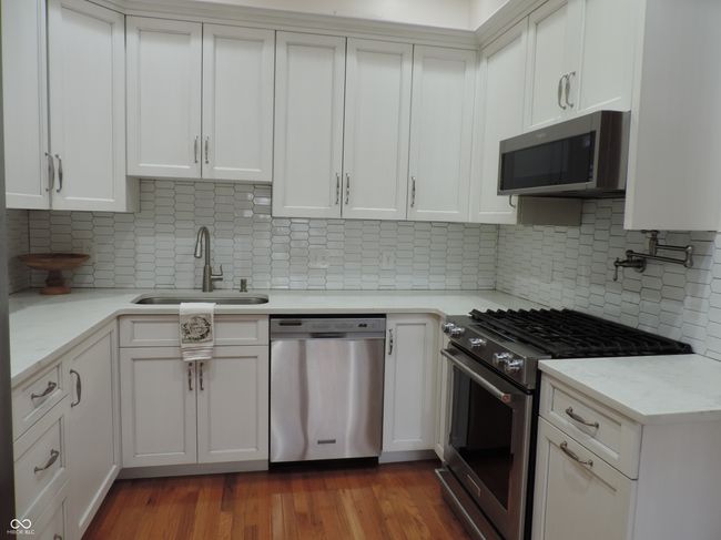 kitchen featuring appliances with stainless steel finishes, white cabinetry, and a sink | Image 8