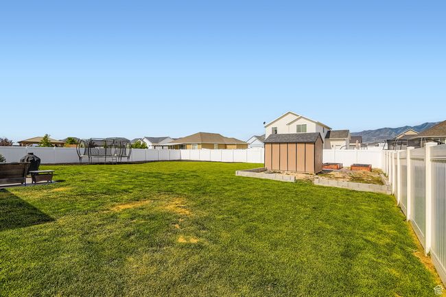 Fenced backyard featuring a trampoline and a storage unit | Image 21