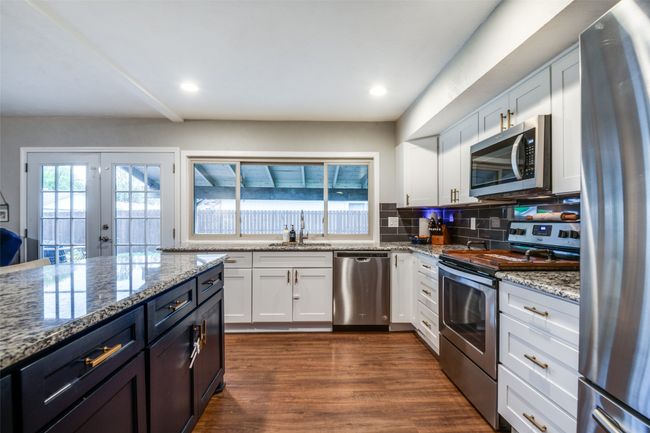 Kitchen featuring light stone counters, dark wood finished floors, white cabinets, and stainless steel appliances | Image 8
