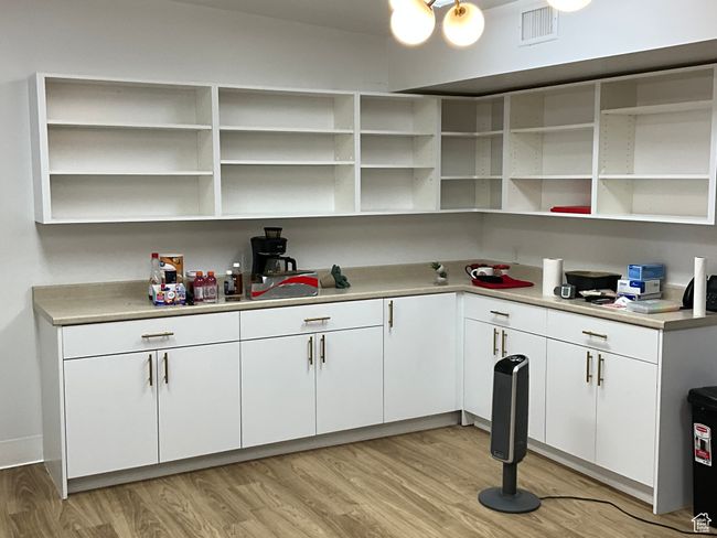 Interior space with white cabinets, light wood-style floors, open shelves, and visible vents | Image 16