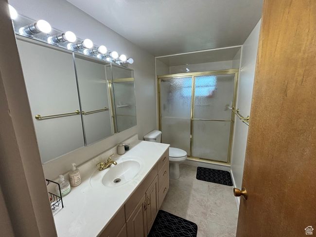 Bathroom with toilet, a stall shower, vanity, and tile patterned floors | Image 12