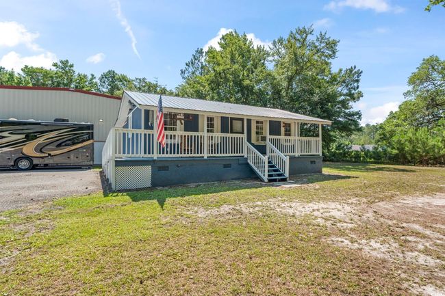 View of front of house featuring covered porch, crawl space, a front lawn, and a metal roof | Image 19