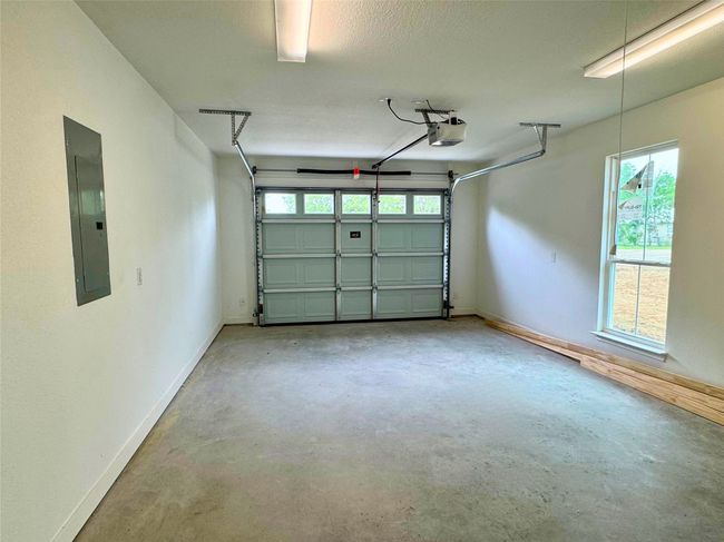 Garage with baseboards, a garage door opener, and electric panel | Image 12