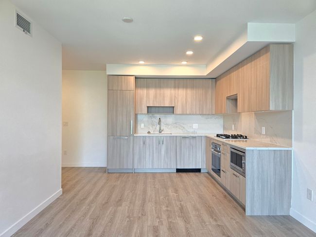 Kitchen featuring modern cabinets, stainless steel appliances, light countertops, light brown cabinets, and light wood-style flooring | Image 4