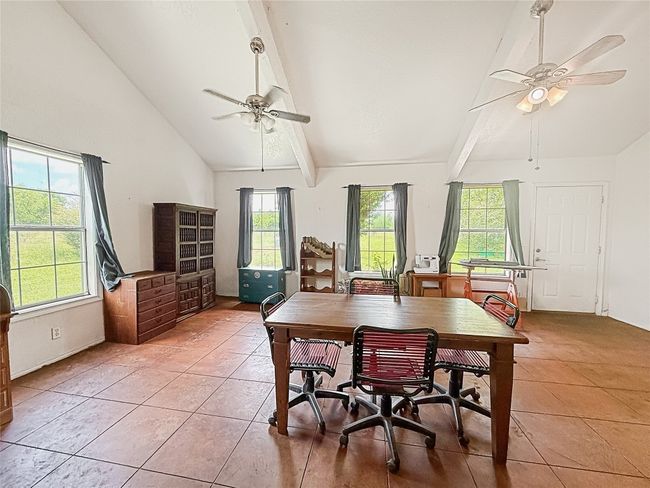 Dining area featuring beam ceiling, light tile patterned floors, a ceiling fan, and high vaulted ceiling | Image 4