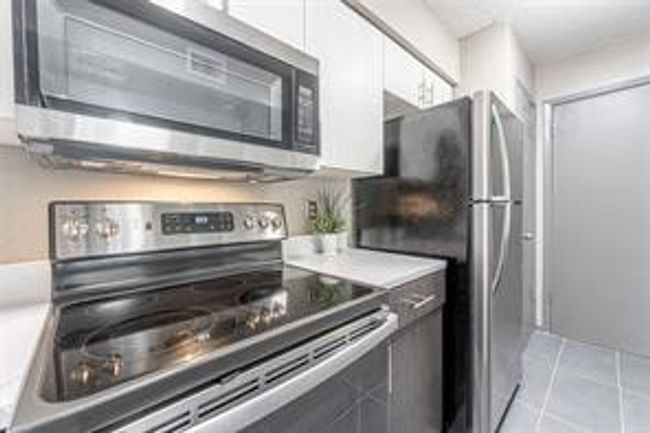 Kitchen with stainless steel appliances, light countertops, and light tile patterned floors | Image 10