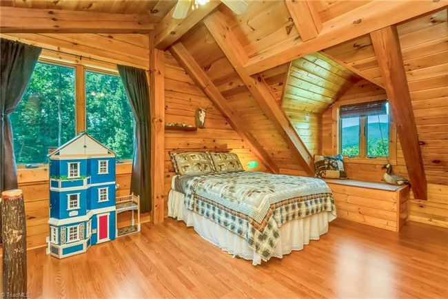 The upper-level bedroom in the log cabin offers captivating mountain views, while a mirrored second bedroom on the opposite side of the loft provides additional space and comfort, combining serene natural surroundings with cozy accommodation. | Image 35