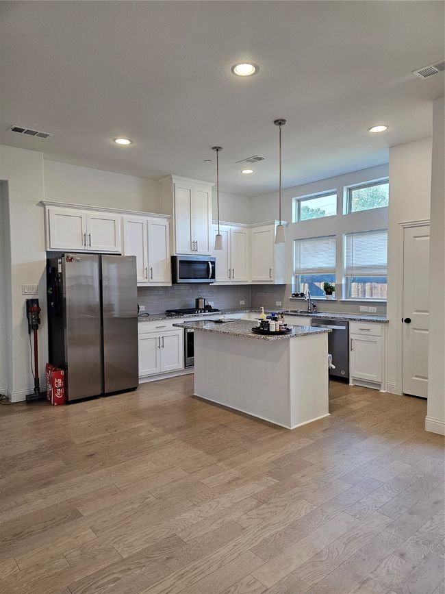Kitchen featuring refrigerator, dishwasher, light wood-style flooring, white cabinets, and recessed lighting | Image 6